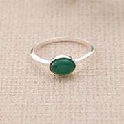 Sterling silver ring with a green Emerald stone on a beige fabric background