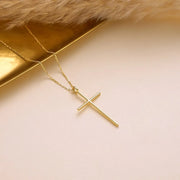14k Gold cross necklace on a soft beige background
