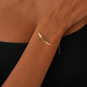 14k Gold bracelet with a green Emerald gemstone on a woman's wrist against a black background