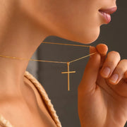 14k Gold necklace with a cross pendant worn by a person against a neutral background