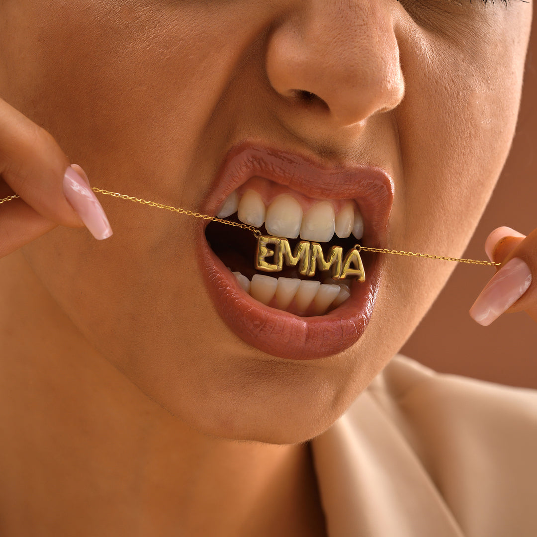 Person wearing a gold chain with 'EMMA' on it around their neck.