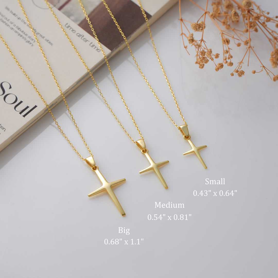 Three gold cross necklaces with size labels on a light background
