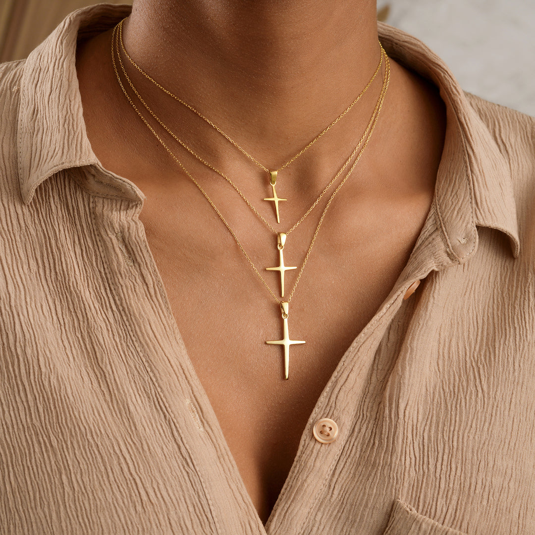 Gold cross necklace on a person wearing a beige shirt