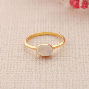 14k Gold filled ring with a white stone on a beige fabric background