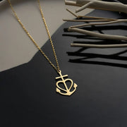 14k Gold necklace with a heart, cross and anchor pendant on a dark surface
