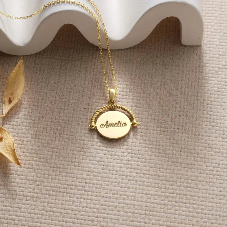 14k Gold filled fidget spinner pendant necklace with a pendant engraved with 'Amelia' on a textured surface.