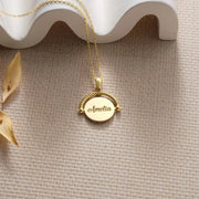 14k Gold filled fidget spinner pendant necklace with a pendant engraved with 'Amelia' on a textured surface.