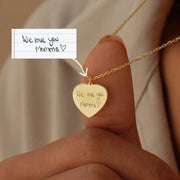 14k Gold heart-shaped pendant necklace with 'We love you Momma' engraving, held by a hand.