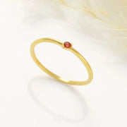 14k Gold-filled mini birthstone ring with a red gemstone on a white background