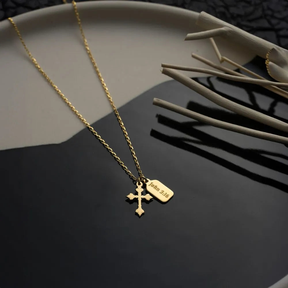 14k Gold necklace with a cross pendant and engraved vertical bar pendant on a dark surface