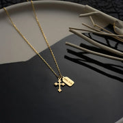 14k Gold necklace with a cross pendant and engraved vertical bar pendant on a dark surface