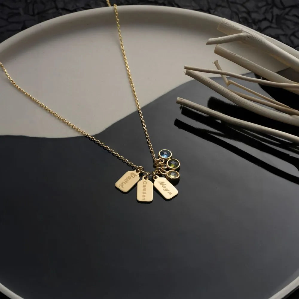 14k Gold necklace with mini charms and cubic zirconia gemstones on a black surface