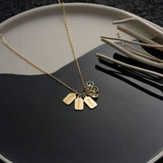 14k Gold necklace with mini charms and cubic zirconia gemstones on a black surface