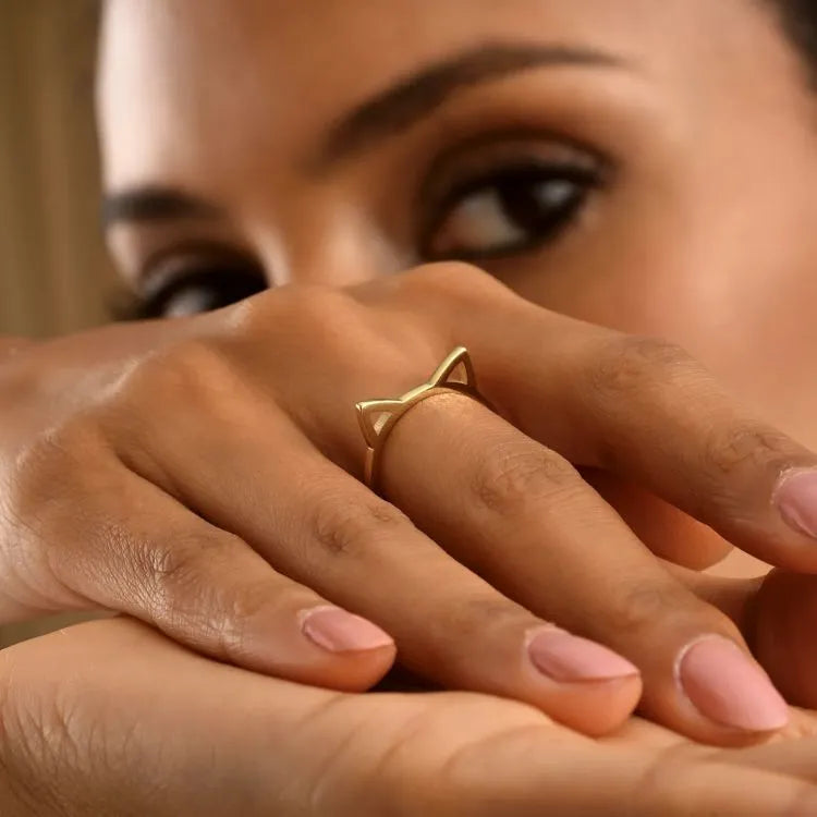 Close-up of a hand wearing a 14k gold filled cat ears ring with a blurred background