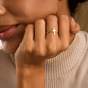 Close-up of a woman model wearing a 14k gold filled cross ring on her finger.