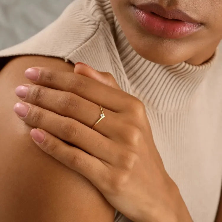 Close-up of a hand wearing a 14k gold filled chevron ring with a diamond, resting on a shoulder.