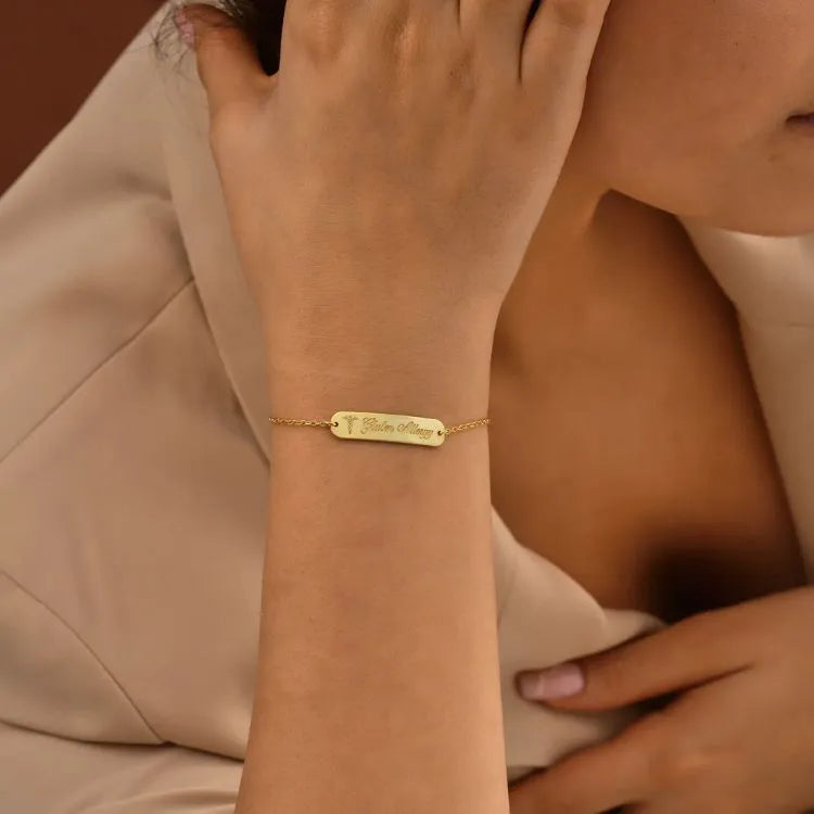 14k Gold filled bar bracelet with engraved words on wrist against a neutral background
