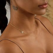 Close-up of a woman model wearing a delicate 14k gold filled necklace with a dainty cut-out birth flower pendant.