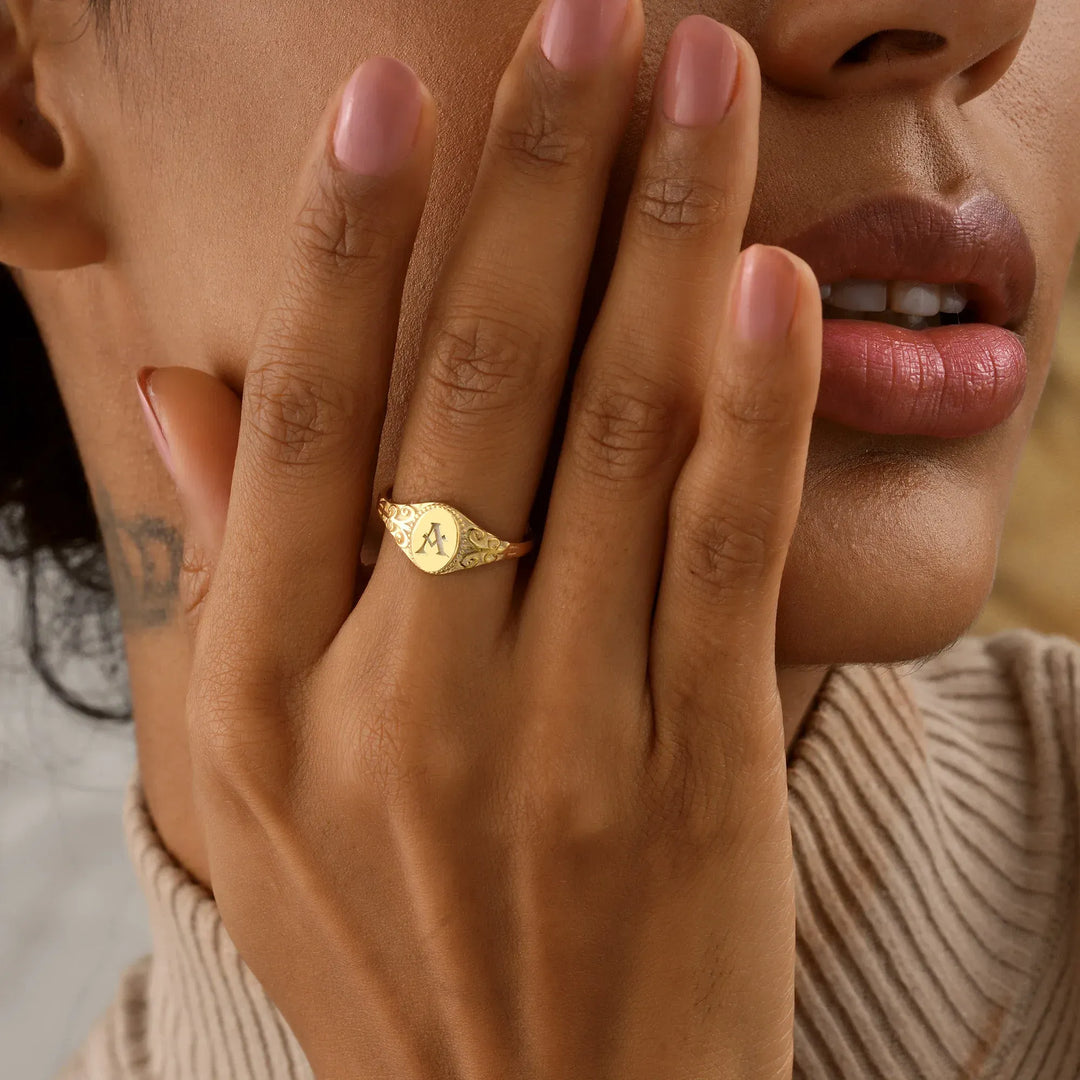 Close-up of a 14k gold filled oval signet ring with initial A engraving, worn on hand