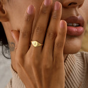 Close-up of a 14k gold filled oval signet ring with initial A engraving, worn on hand