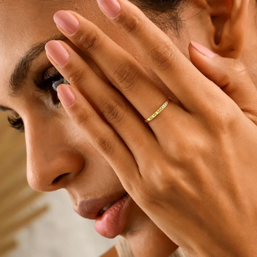 Close-up of a woman with a 14k gold-filled ring on her finger, holding her hand to her face.