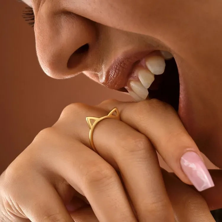 Close-up of a hand wearing a 14k gold filled cat ear ring with a blurred background