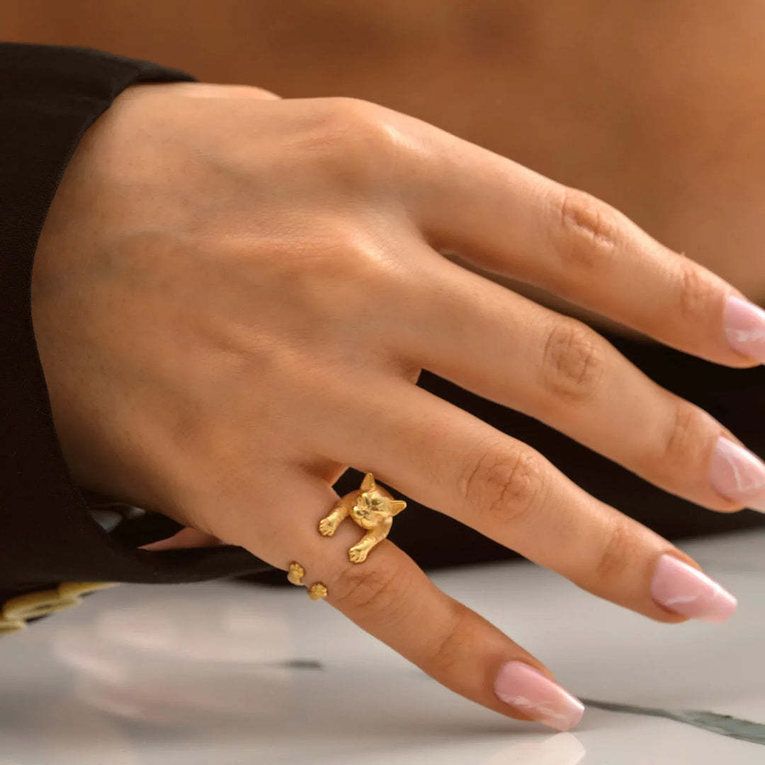 Hand wearing a 14k gold filled ring with a small pug design on a neutral background