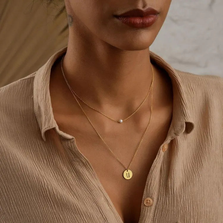 Close-up of a woman model wearing a 14k gold filled pearl disc layer necklace.