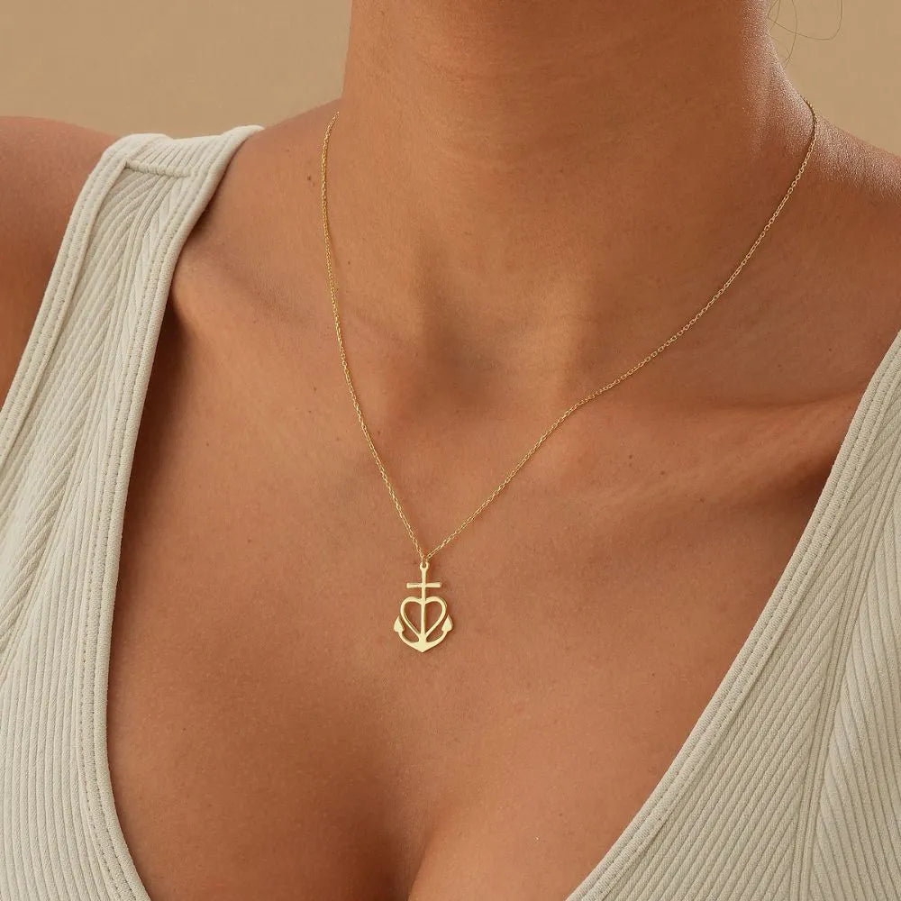 14k Gold necklace with a heart, cross and anchor pendant on a dark surface