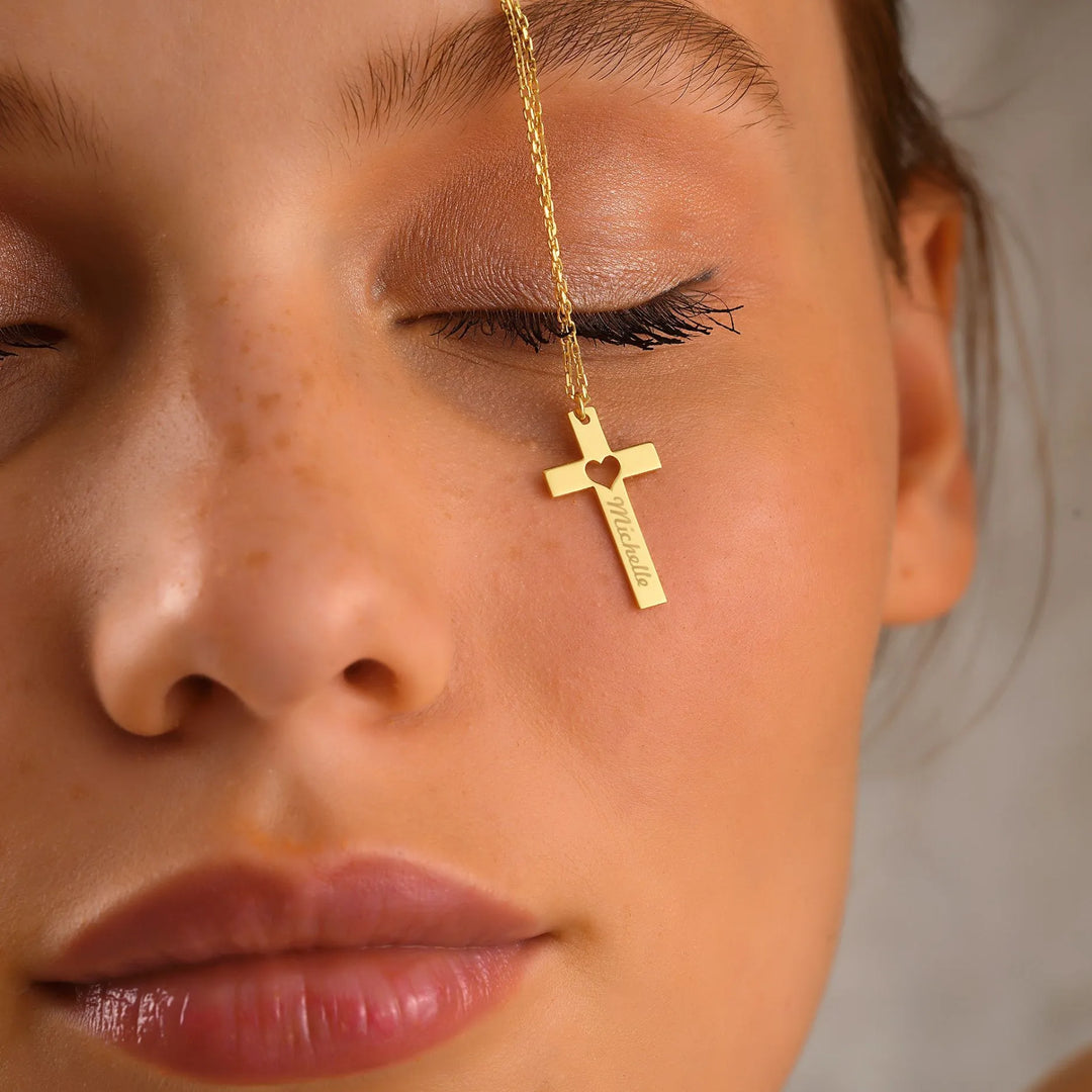 Close-up of a woman's face with a 14k gold personalized cross necklace.