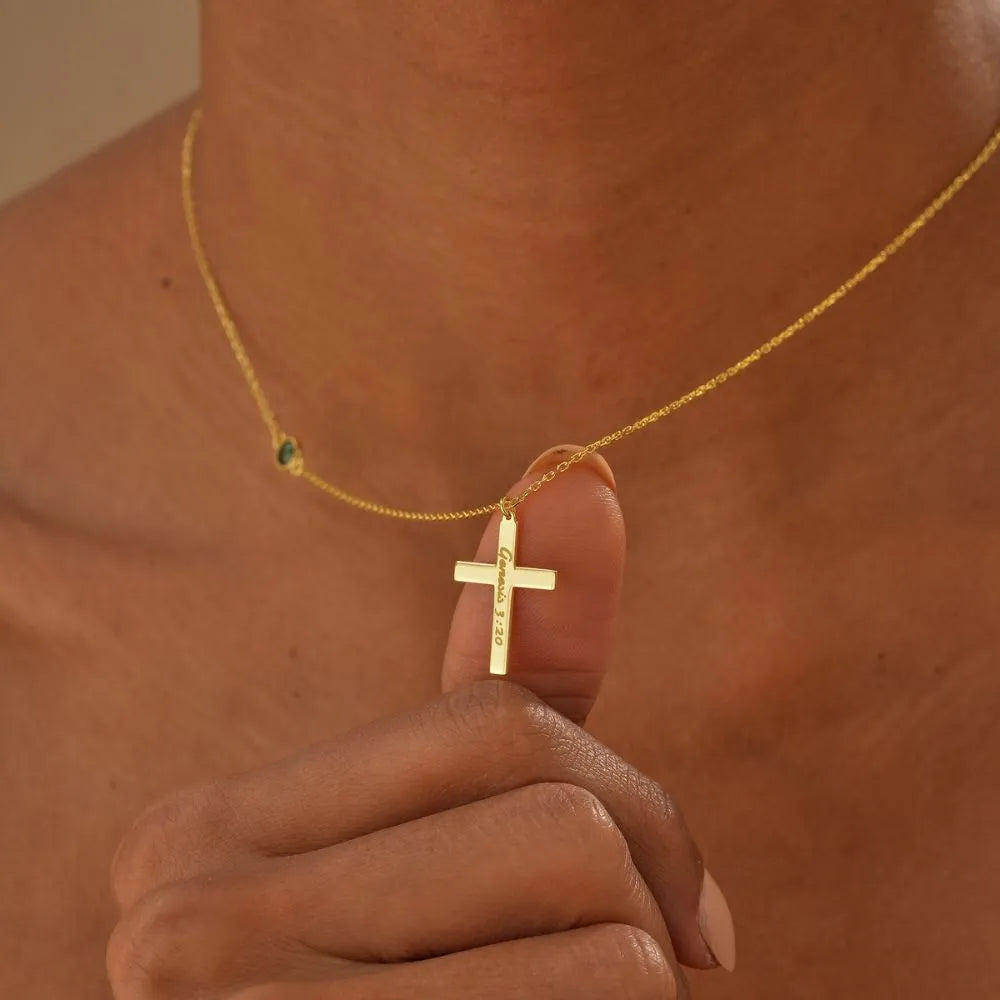 14k Gold necklace with a cross pendant held by a hand against a neutral background
