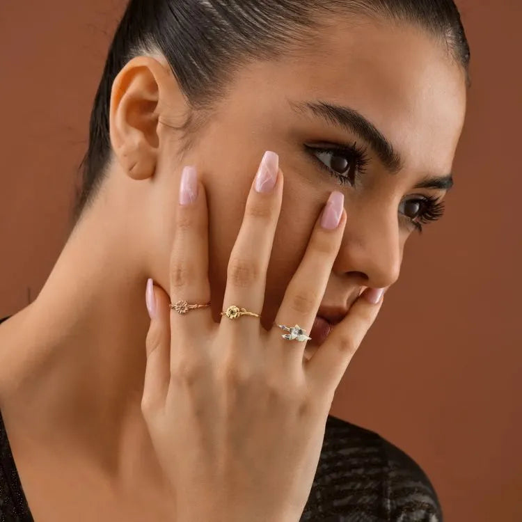 Woman model with 14k gold filled cut out birth flower ring on finger against a brown background