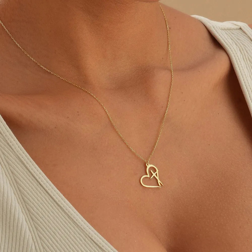 14k Gold necklace with a heart-shaped cross pendant on a person wearing a beige top.