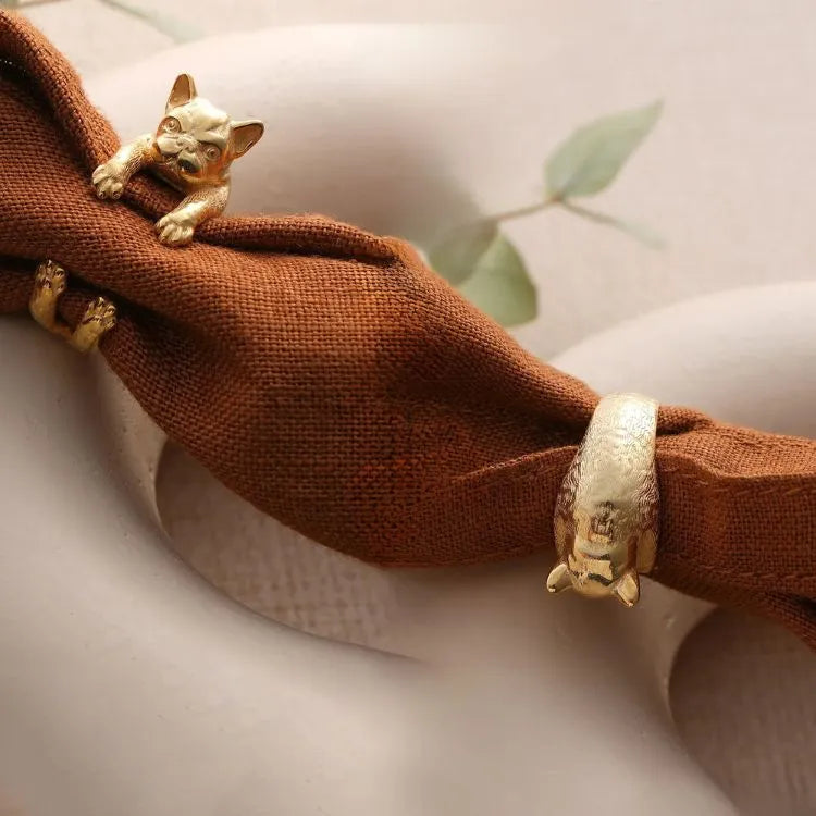 14k Gold filled pug-shaped rings on a brown napkin with a white background