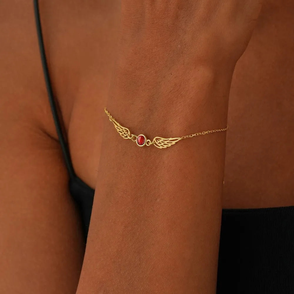 14k Gold bracelet with a red Garnet gemstone on a person's wrist against a brown background