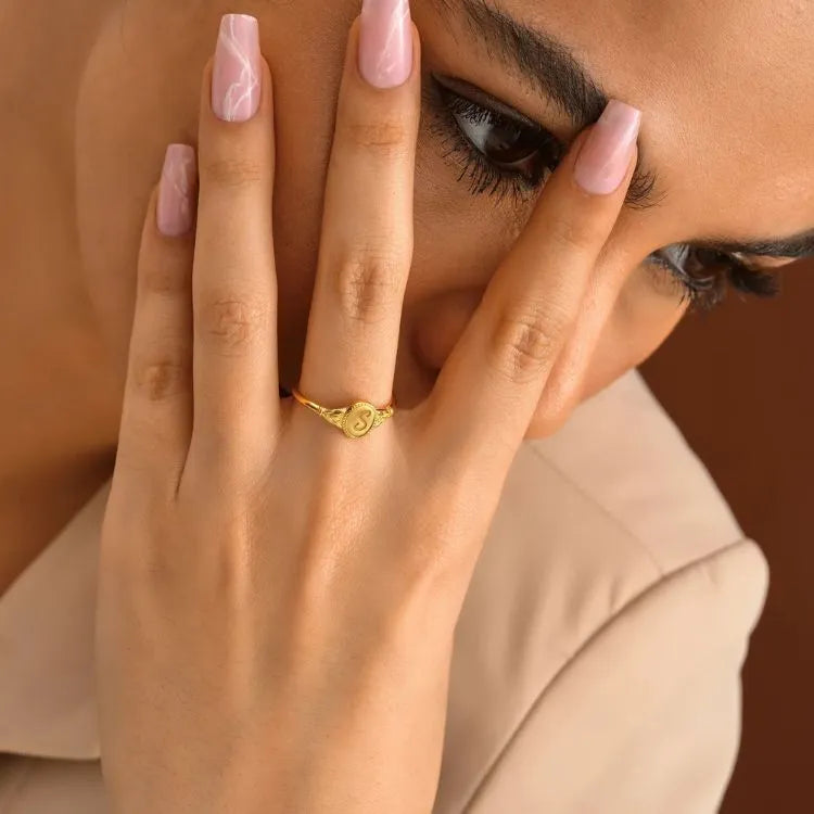 Close-up of a hand wearing a 14k gold filled ring with a blurred background