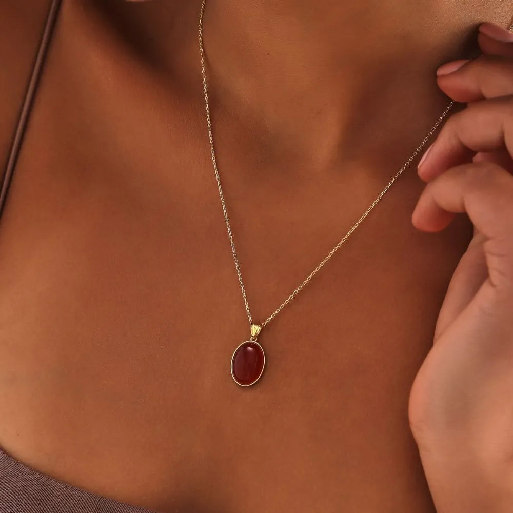 14k Gold necklace with a reddish carnelian pendant on a person's neck