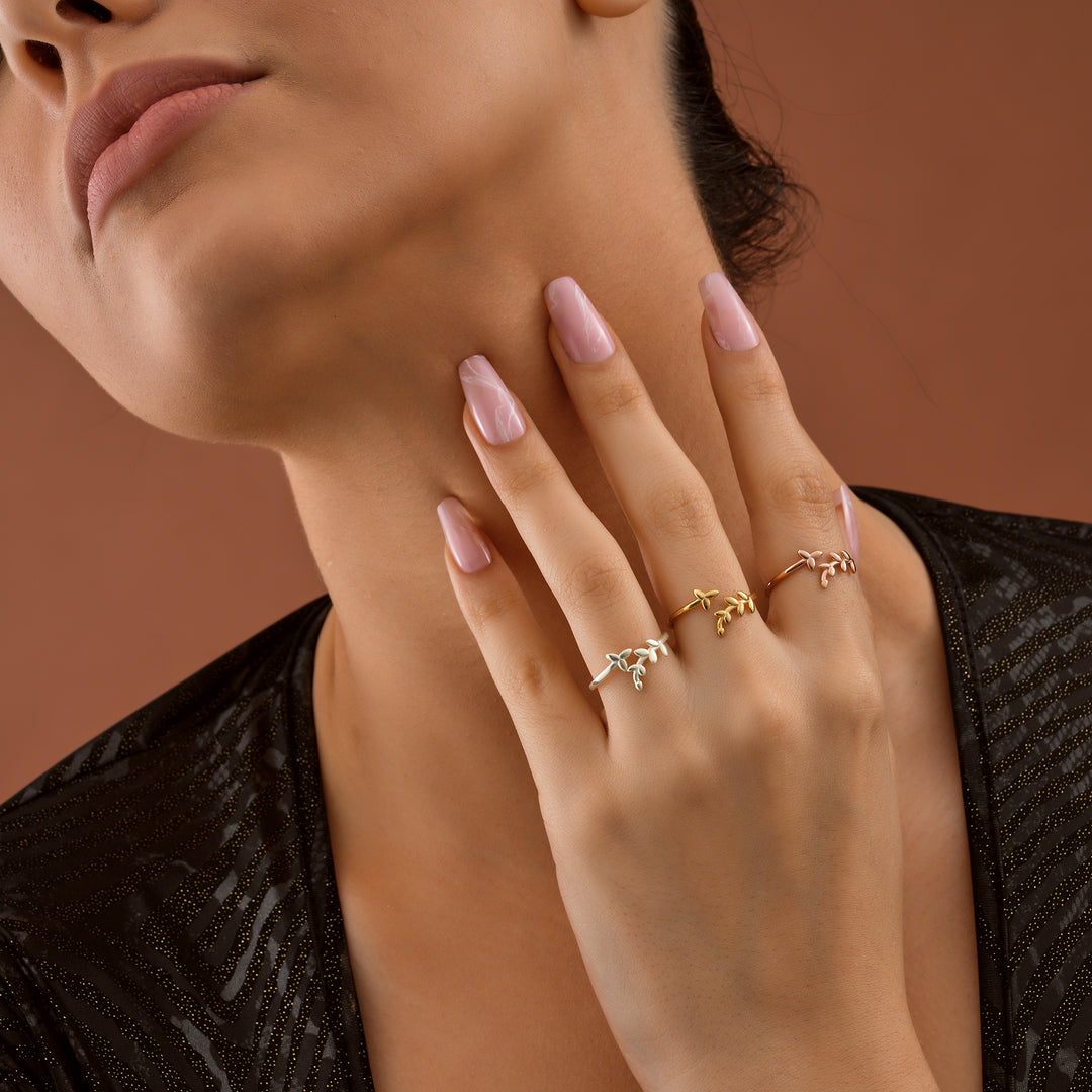 Olive Leaf Ring - Close-up of a woman's hand wearing multiple rings on a brown background