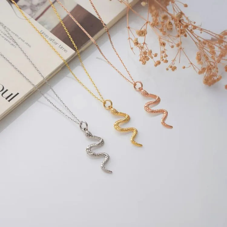 Three snake necklaces with different material colors on a white surface with dried flowers.
Materials:
Sterling silver,
14k gold filled,
14k rose gold filled.