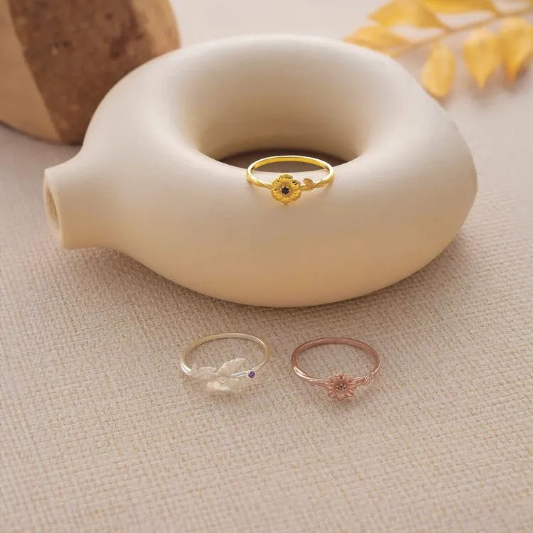 Three cut out birth flower rings, with different color (materials), on a textured surface with a ceramic object in the background.
Materials:
14k gold filled (on the top)
925 sterling silver (left bottom)
14k rose gold filled (right bottom)