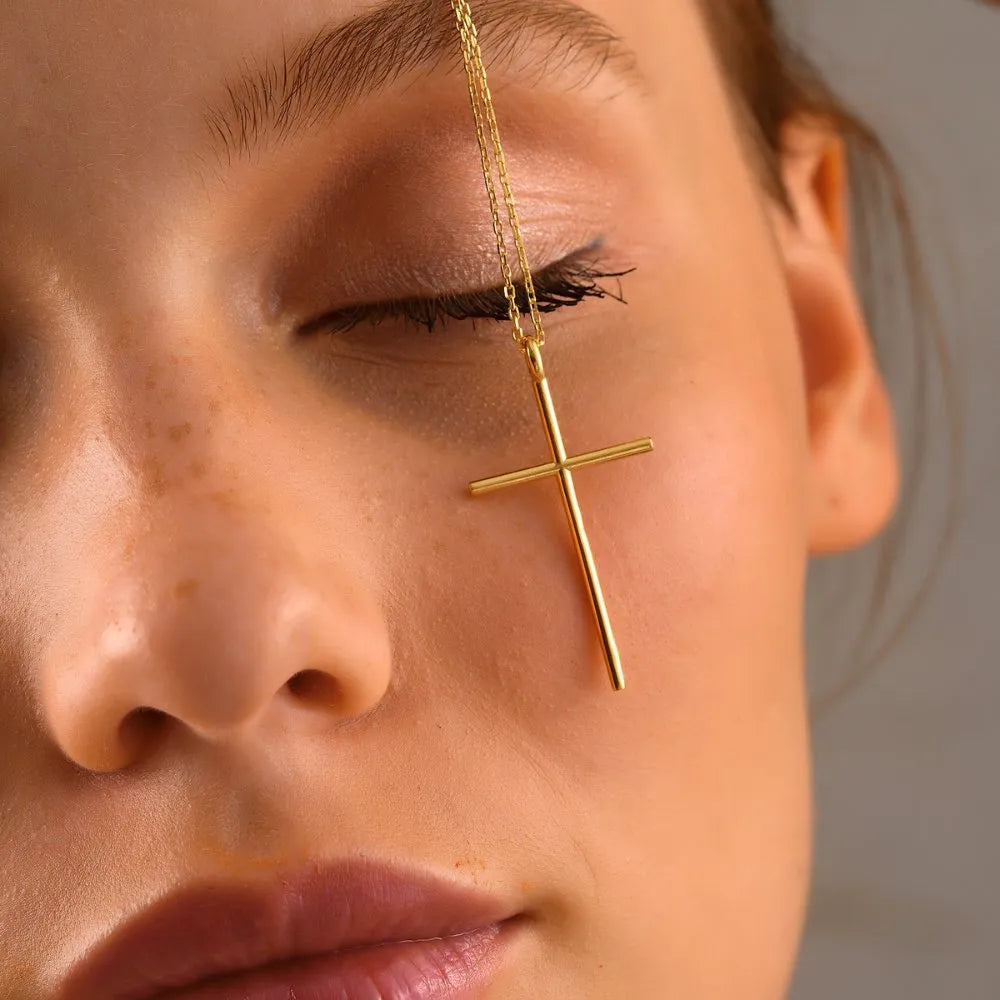Close-up of a woman wearing a 14k gold cross necklace.