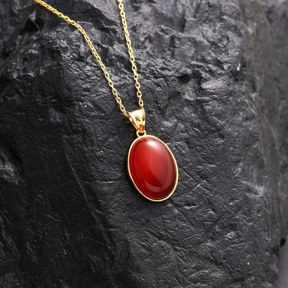 14k Gold necklace with a red Carnelian pendant on a dark stone surface