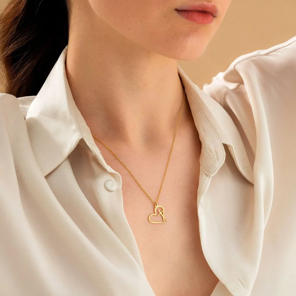14k Gold heart cross necklace worn by a woman model in a light-colored shirt against a neutral background