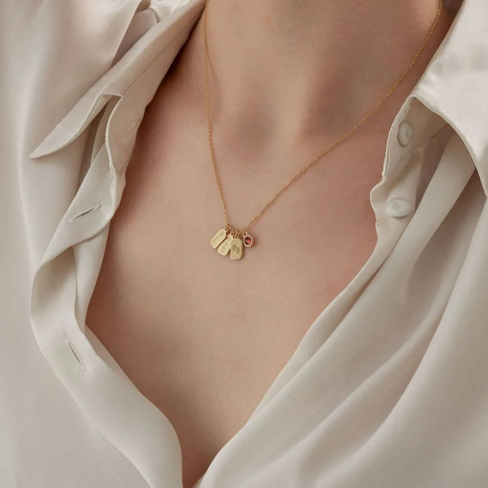 14k Gold necklace with heart-shaped pendants on a person wearing a white shirt.