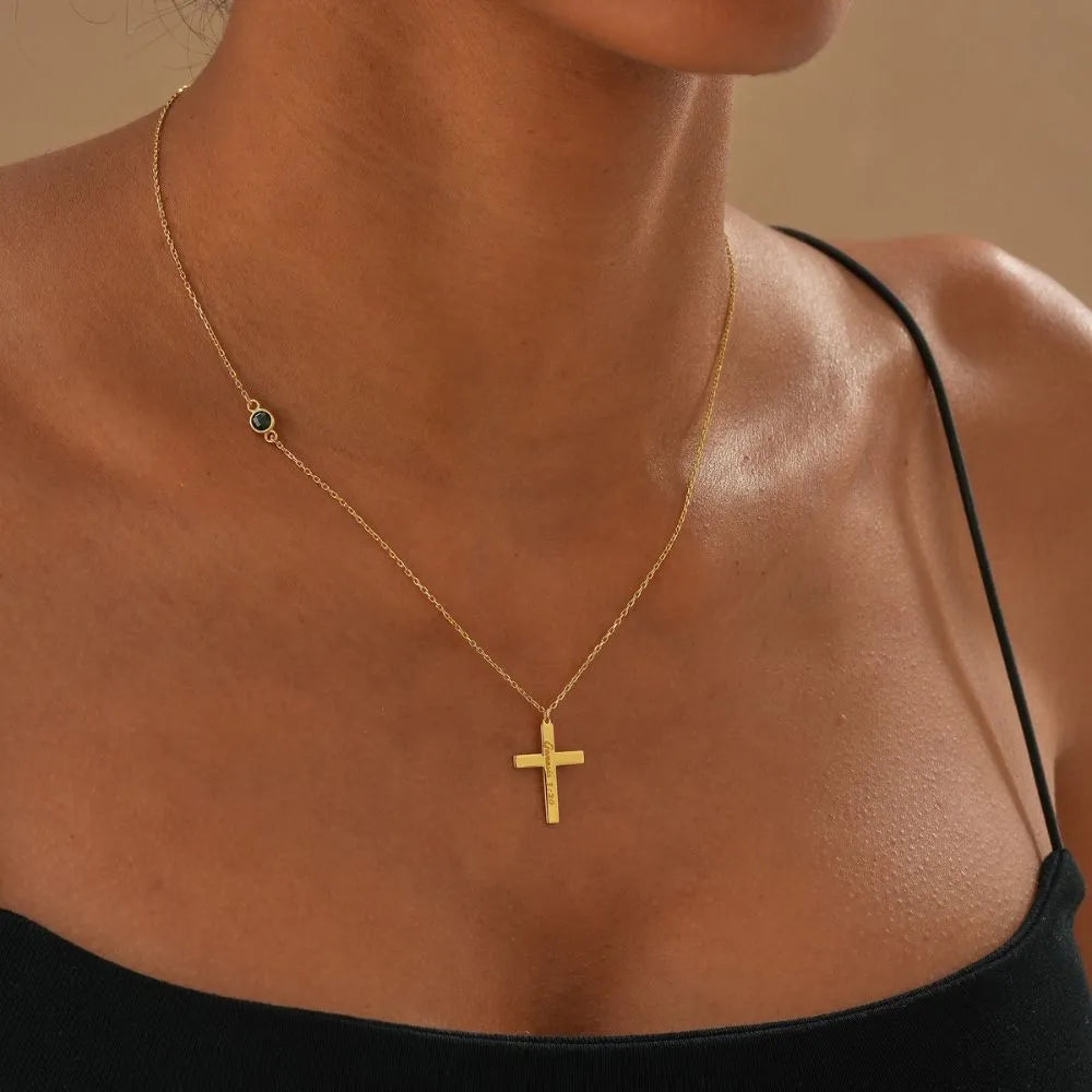 14k Gold necklace with a cross pendant on a person wearing a black top against a beige background