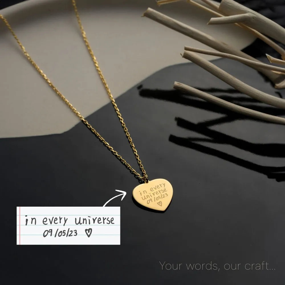 14k Gold necklace with a heart-shaped pendant on a dark surface with a white label.